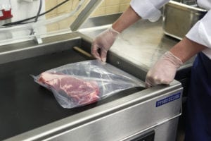 Meat packaging on a conveyor belt, which requires MAP gases